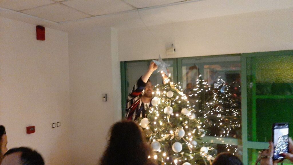 Ο Νίκος Κοκλώνης τοποθετεί το αστέρι στην κορυφή του δέντρου. 