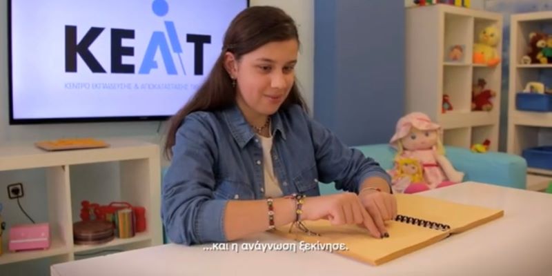 Μαθήτρια με οπτική αναπηρία διαβαζει απτικά ένα βιβλίο braille.