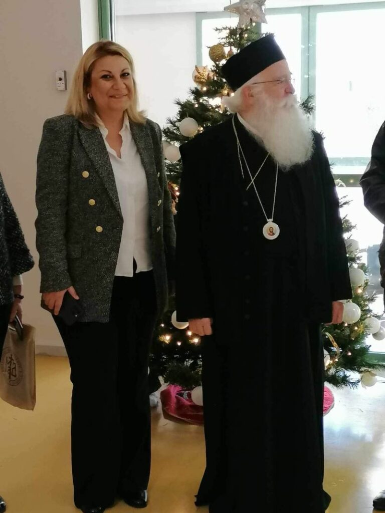 Ο Σεβασμιώτατος Μητροπολίτης Δημητριάδος και Αλμυρού κκ Ιγνάτιος και η Διοικήτρια και Πρόεδρος του ΔΣ του ΚΕΑΤ, κα Σοφία-Λευκή Χαμονικολάου στην είσοδο του ΚΕΑΤ, μπροστά από το χριστουγεννιάτικο δέντρο.