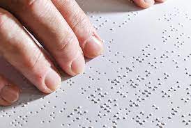 Κείμενο σε Braille και το χέρι ενός ανθρώπου με αναπηρία όρασης  που το διαβάζει.