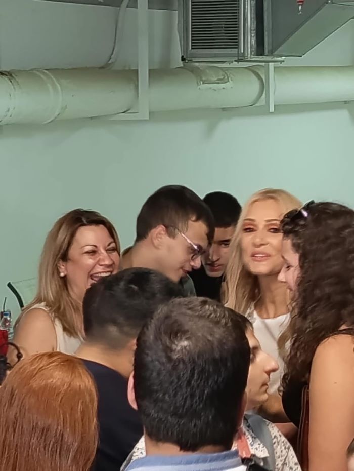 Η Νατάσα Θεοδωρίδου με τη Διοικήτρια του ΚΕΑΤ, κα Σοφία-Λευκή Χαμονικολάου και μαθητές του ΚΕΑΤ συνομιλούν στα παρασκήνια, φωτογραφίζονται μαζί της και είναι όλοι γελαστοί και χαρούμενοι.
