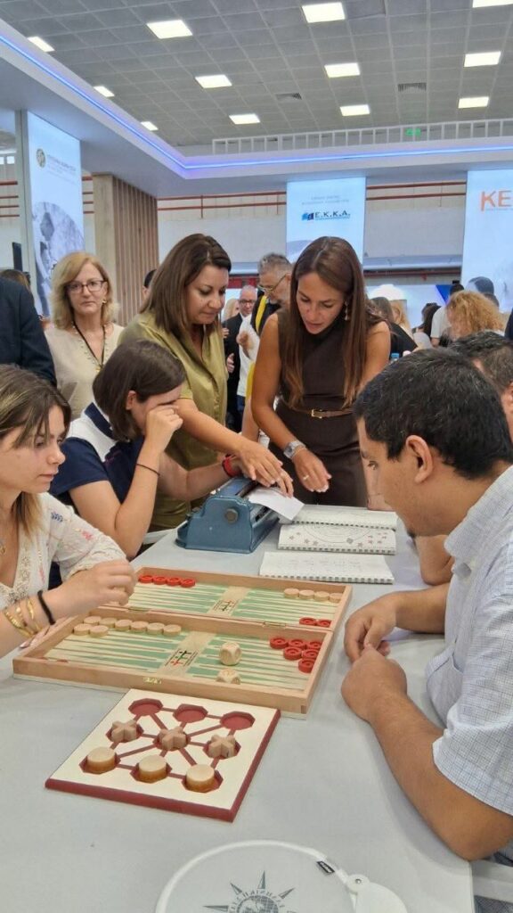 Η Υπουργός Κοινωνικής Συνοχής και Οικογένειας, κα Δομνα Μιχαηλίδου μαζί με τη Διοικήτρια του ΚΕΑΤ, κα Σοφία Λευκή Χαμονικολάου, παρακολουθούν τα παιδιά που γράφουν σε μηχανή Braille. Παρούσα είναι και η Προϊσταμένη Διεύθυνσης του ΚΕΑΤ, κα Μαρία Αζούκη.