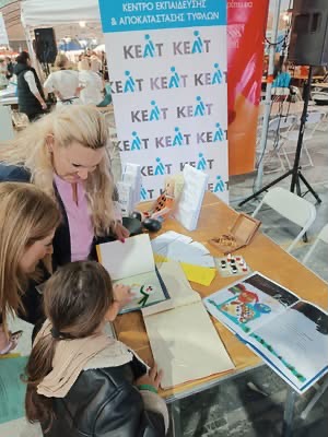 Μητέρα και παιδί ενημερώνονται για τον ρόλο του ΚΕΑΤ και το παιδί επεξεργάζεται ένα απτικό βιβλίο.