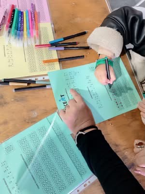 Παιδί γράφει με χρωματιστούς μαρκαδόρους το όνομα του στην γραφή Braille σε ειδικά διαμορφωμένο χαρτί.