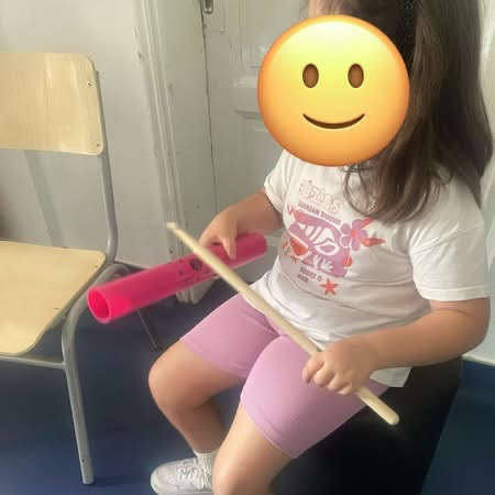 μαθήτρια ακολουθεί το ρυθμό συνδυάζοντας μπαγκέτα και boomwhacker.