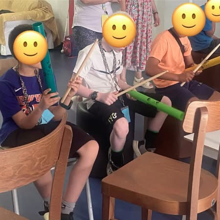 μαθητές κρατούν στα χέρια τους μπαγκέτες και boomwhackers και αναπαριστούν μουσικά  τους ήχους της βροχής.