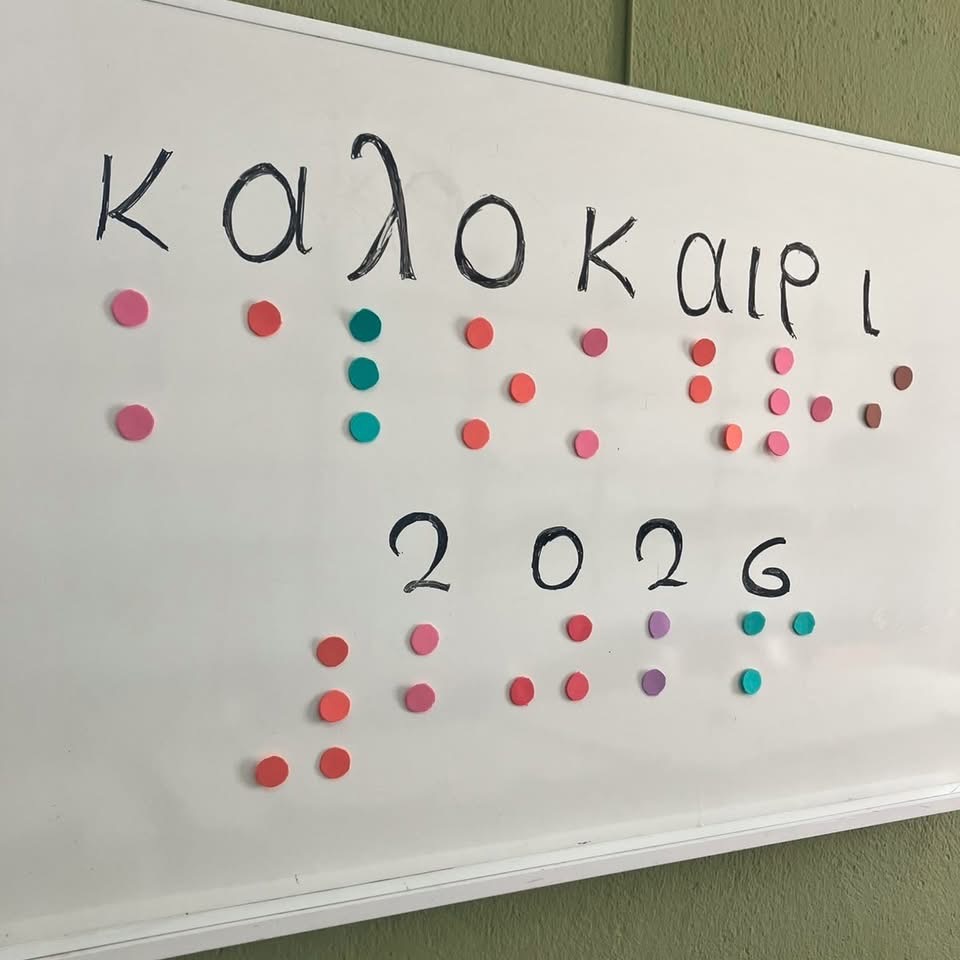 Σε ασπροπίνακα γραμμένο με πολύχρωμες κουκίδες braille και σε γραφή βλεπόντων «Καλοκαίρι 2026»